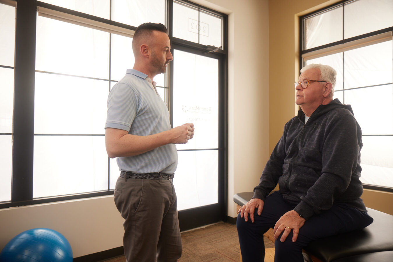 physical therapist and senior patient discussing physical therapy for weakness and aging