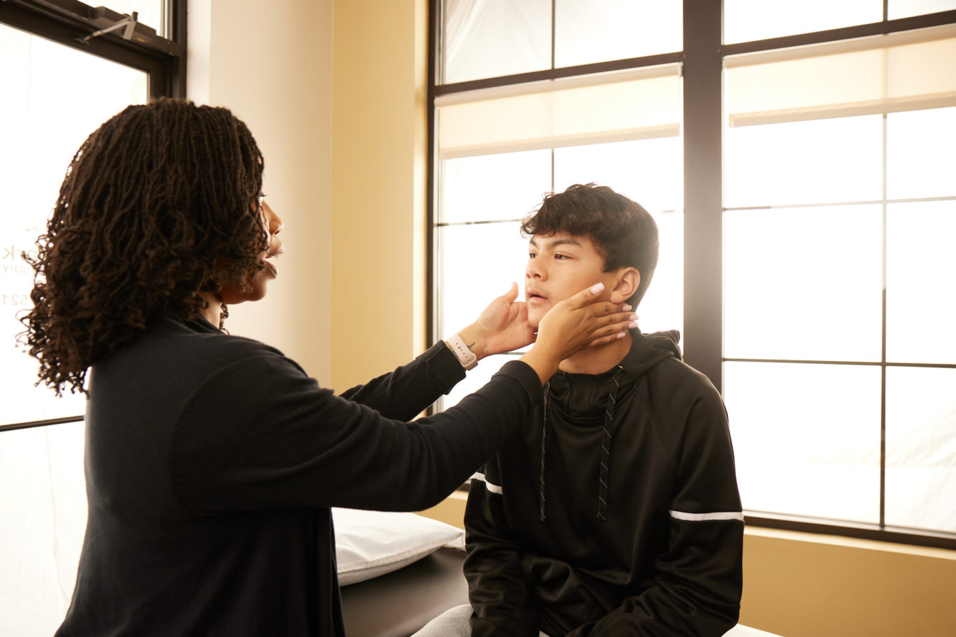 physical therapist examining a young boys jaw