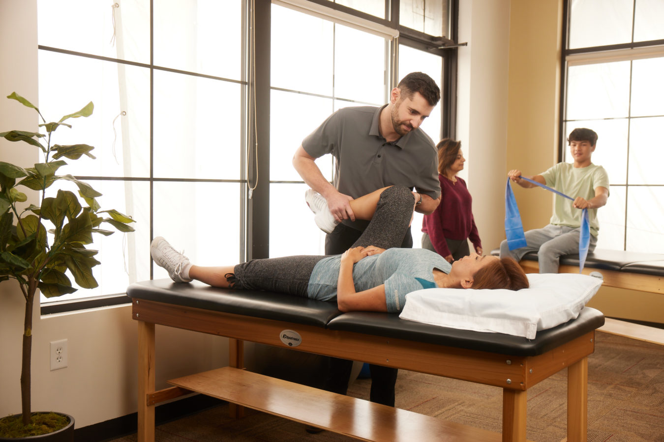 male physical therapist helping female patient stretch her knee