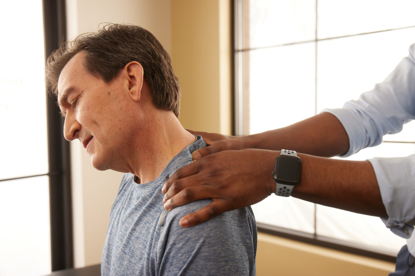 older man getting his neck and shoulders massaged by physical therapist