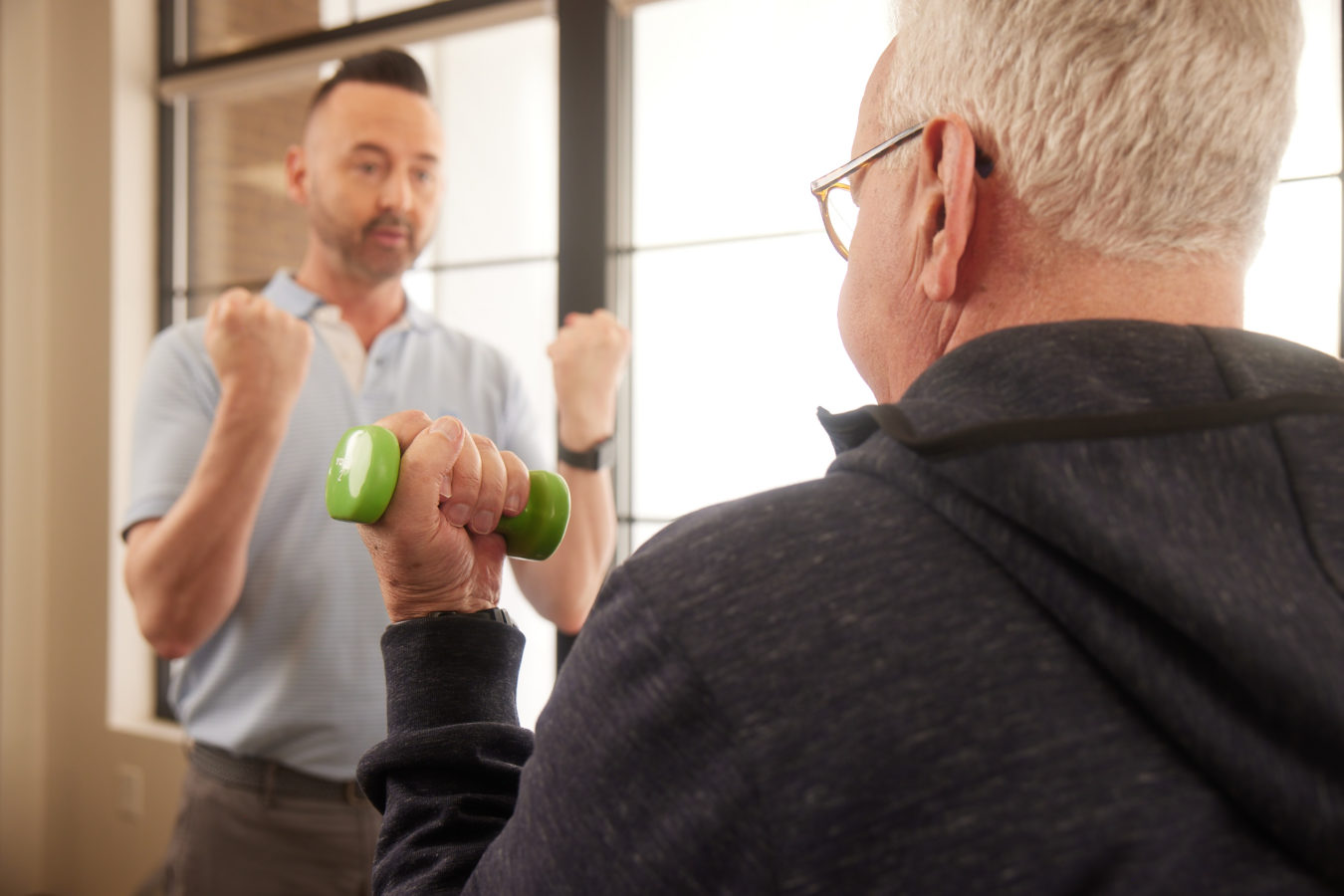 old man lighting weight during physical therapy appointment