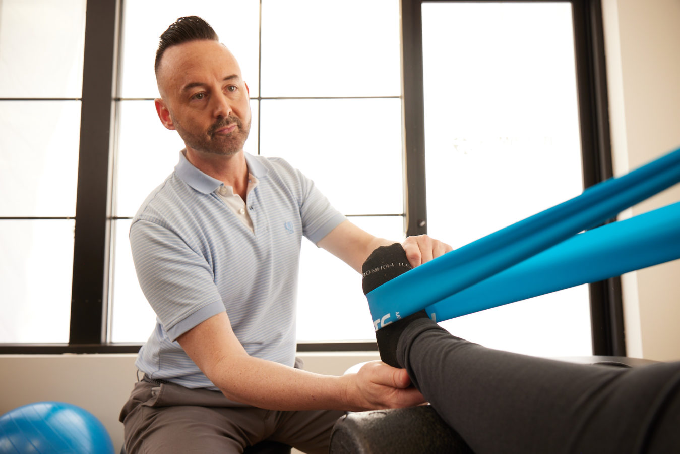 male physical therapist helping patient with exercise band stretches