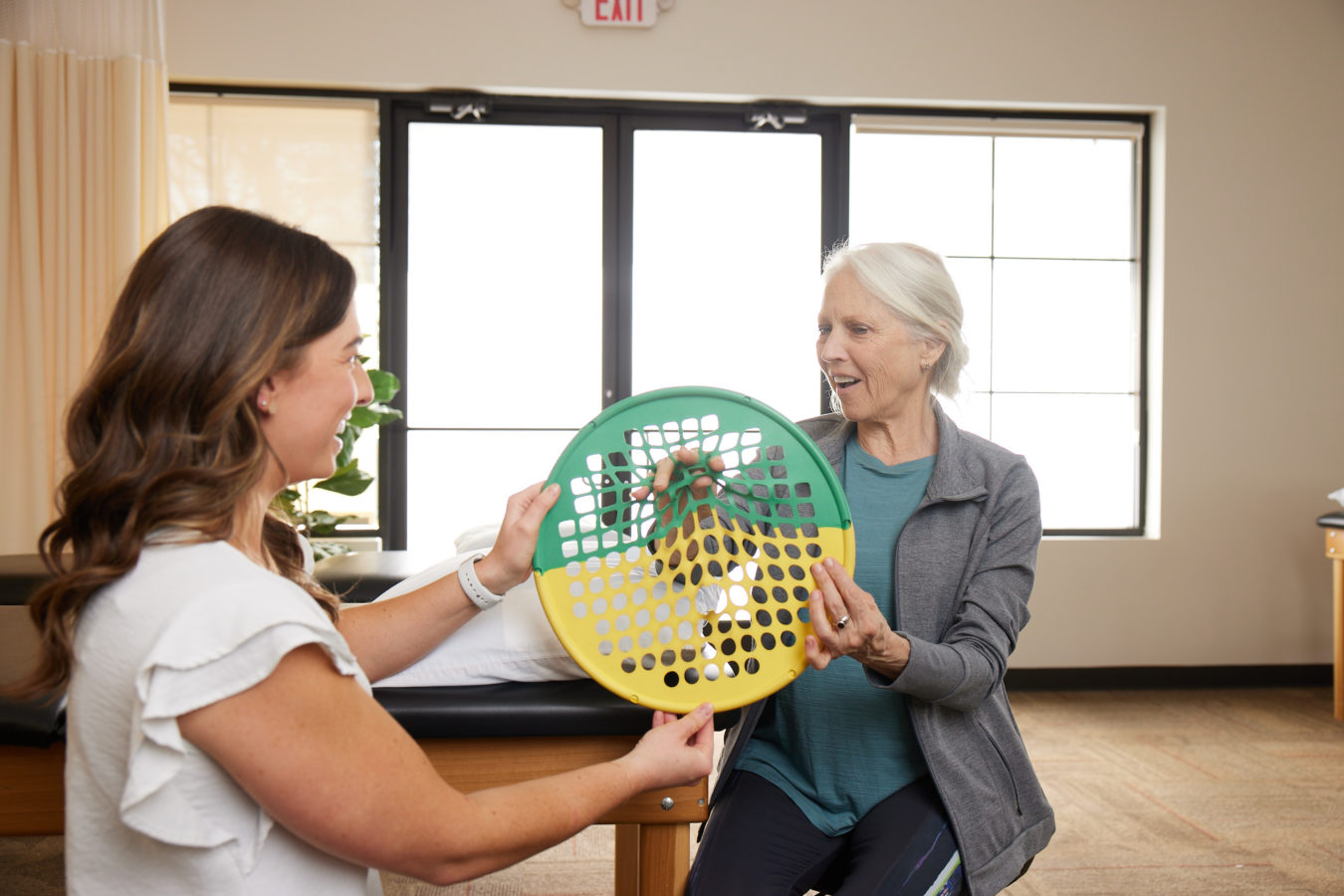 female physical therapist showing older woman hand and wrist exercises