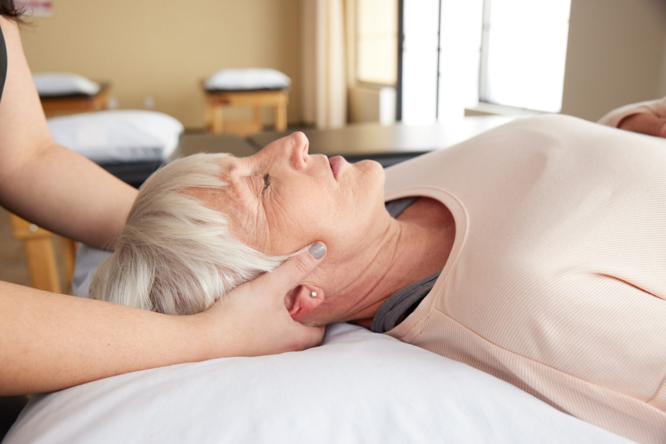 older woman with grey hair laying down during physical therapy exam