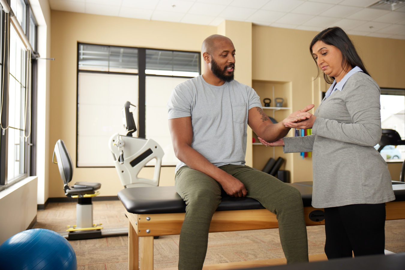 female physical therapist examining her male patients left elbow