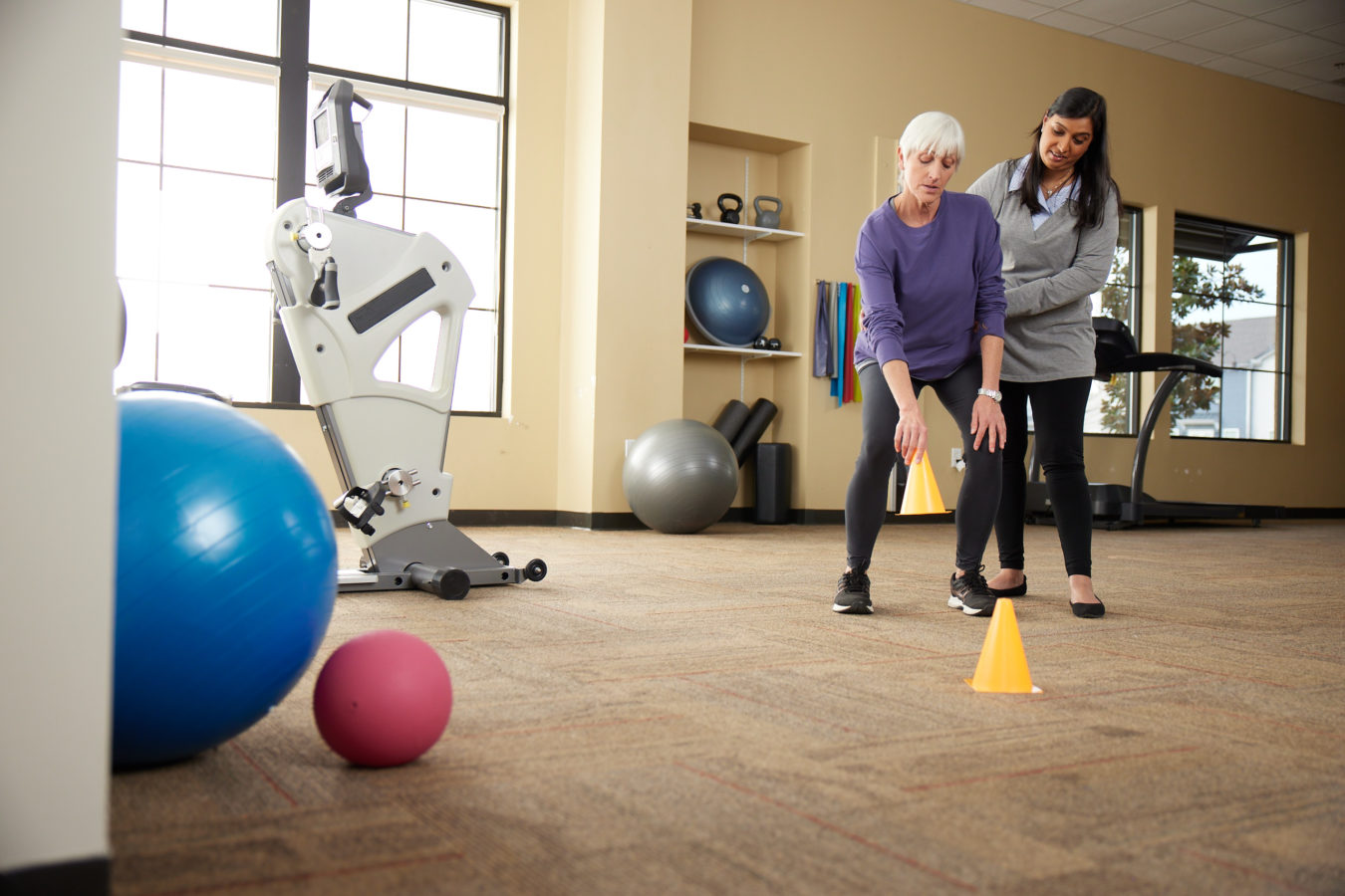 female physical therapist guiding her older female patient through exercises