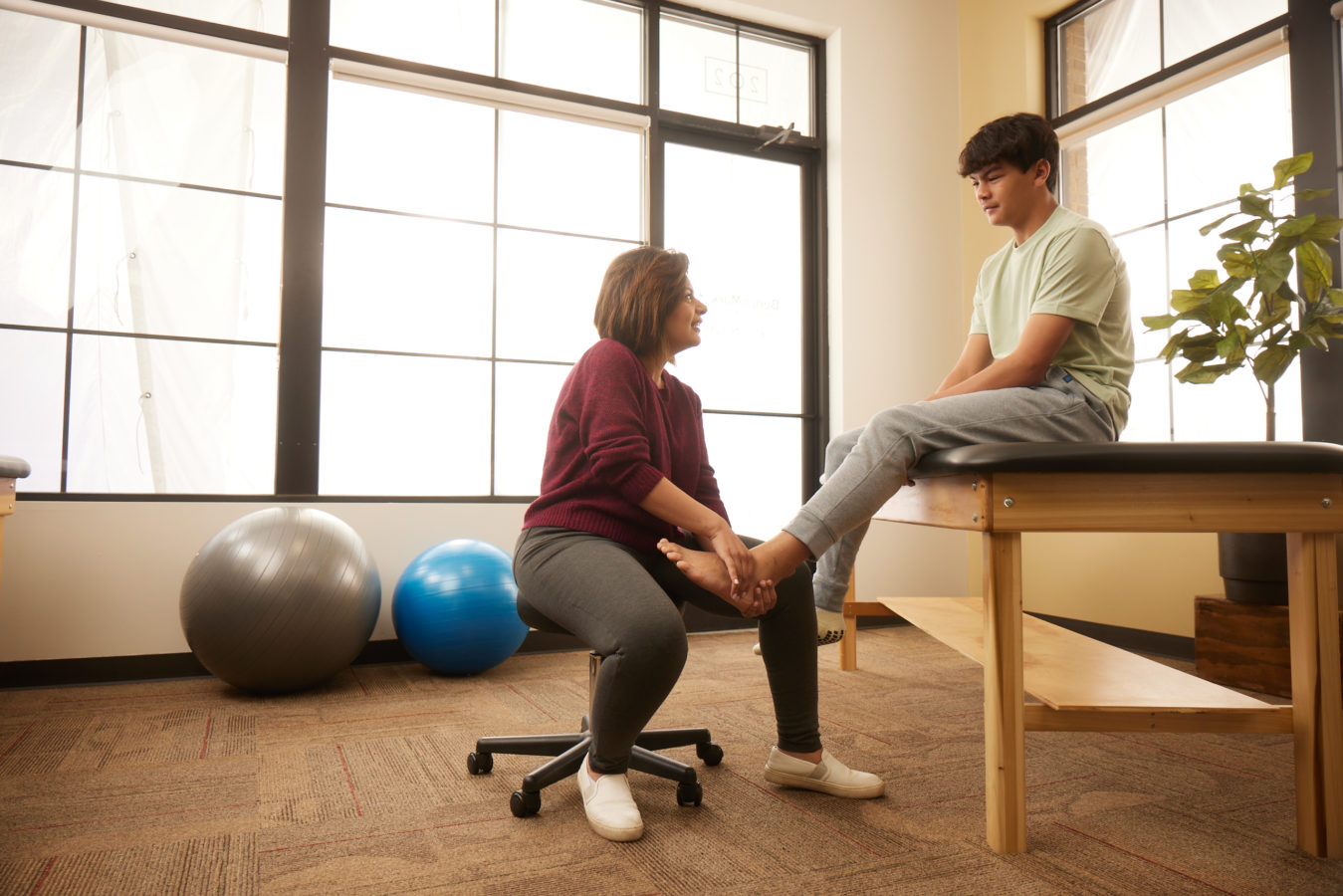 teenage boy getting his foot examined by physical therapist