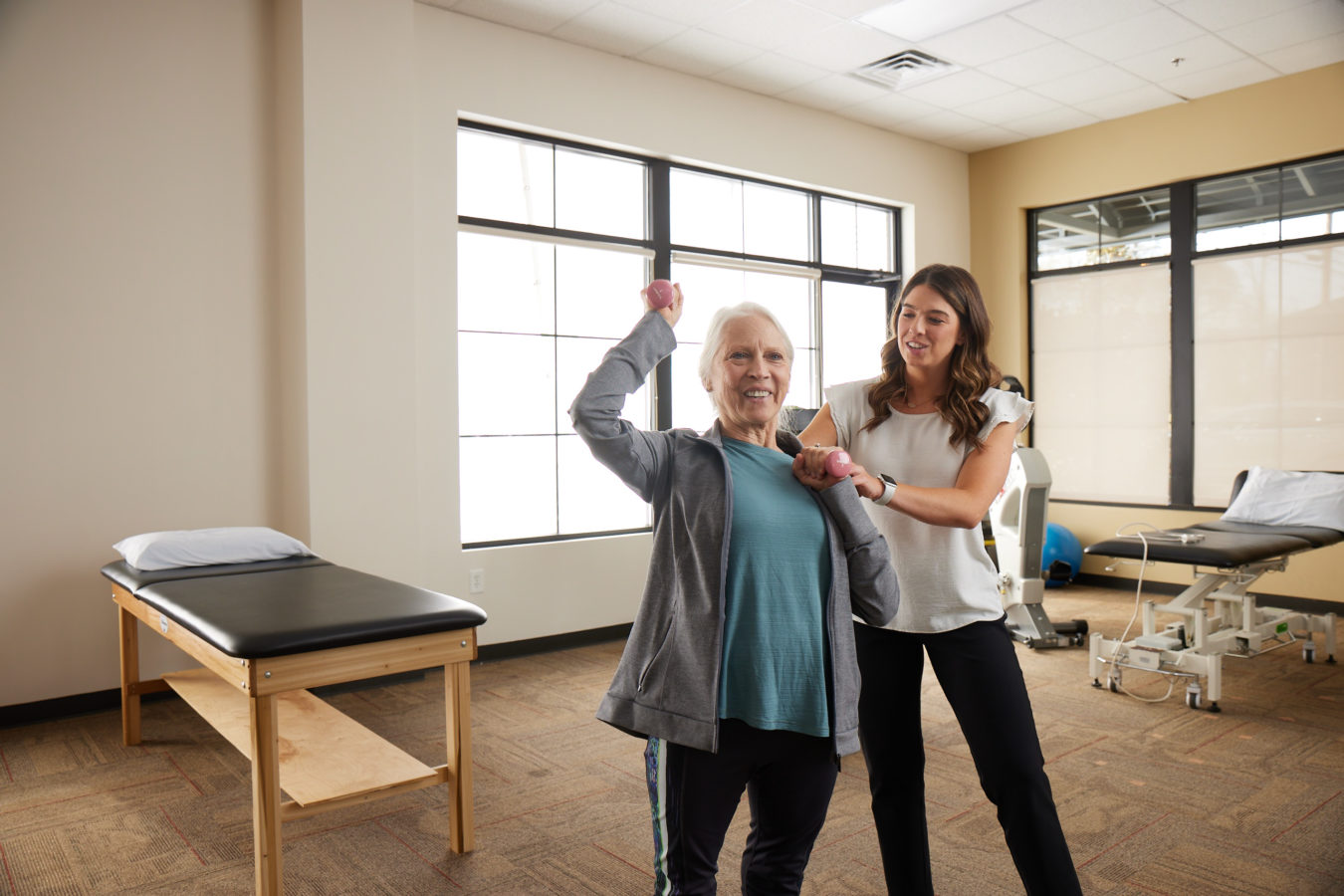 older woman with a blue shirt on lighting small weights during physical therapy appointment