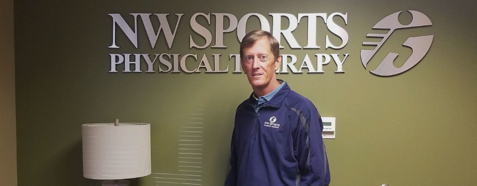 man standing in front of NW Sports Physical Therapy sign