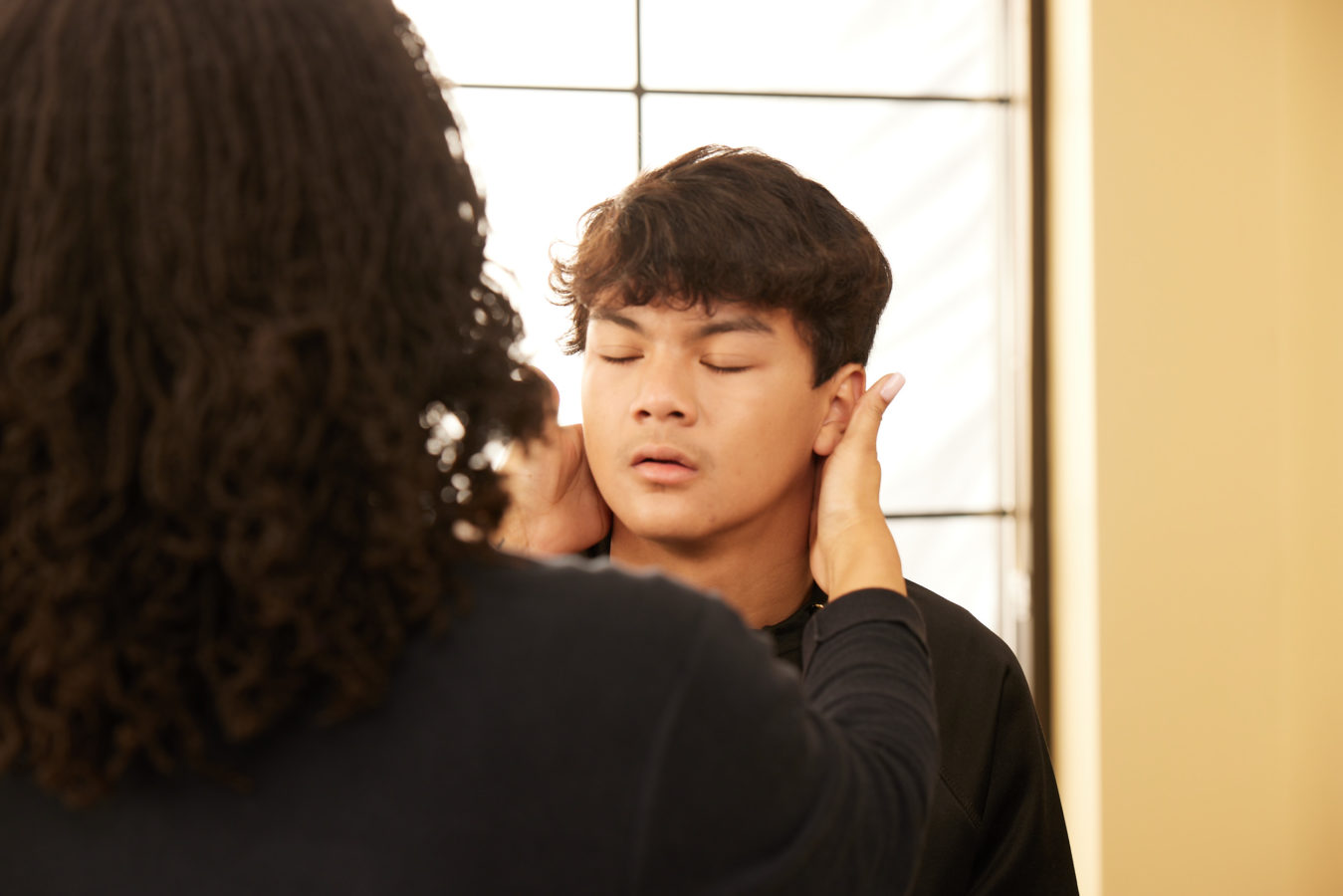 female physical therapist examining teenage boys neck