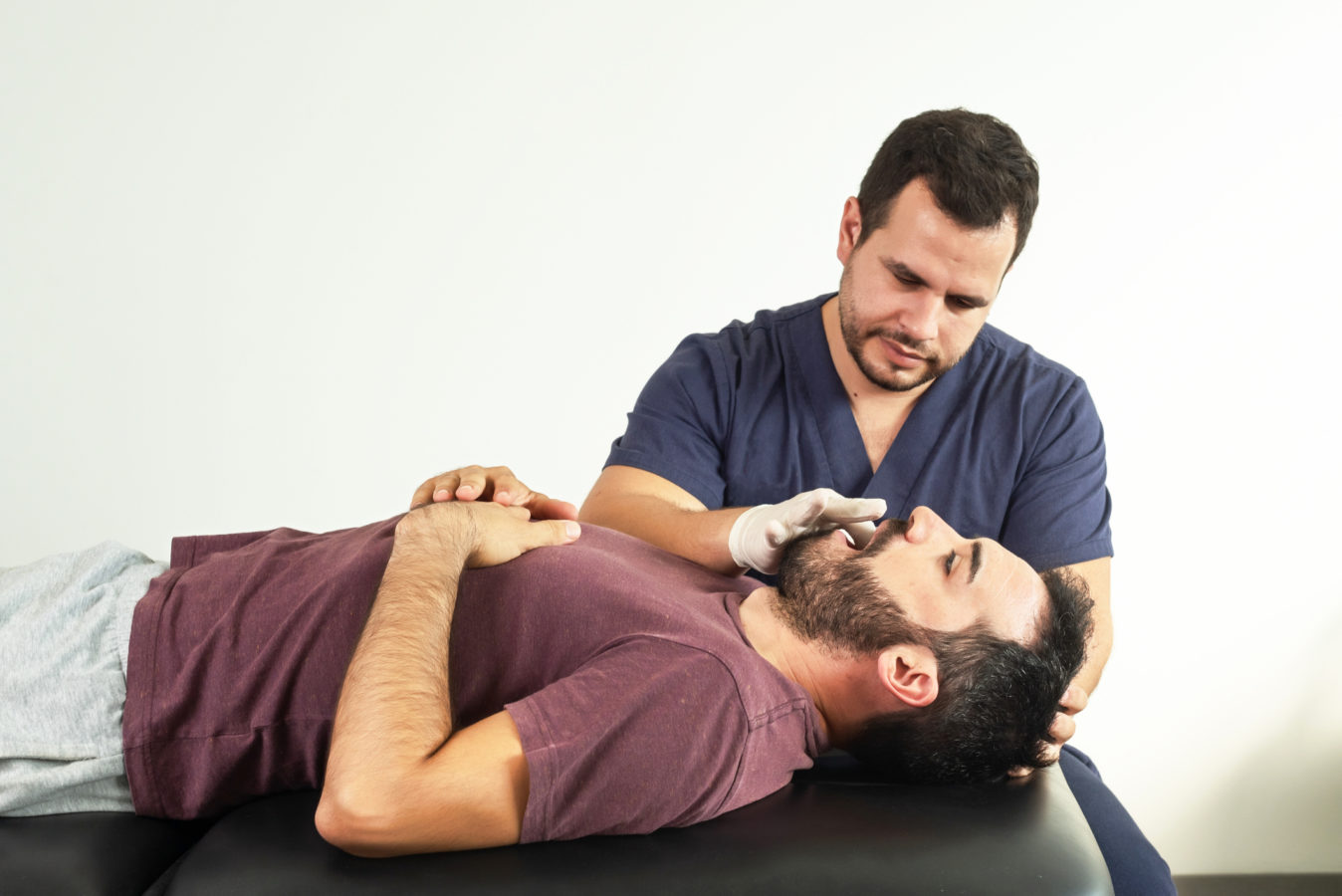Physiotherapist performing a jaw examination on a patient