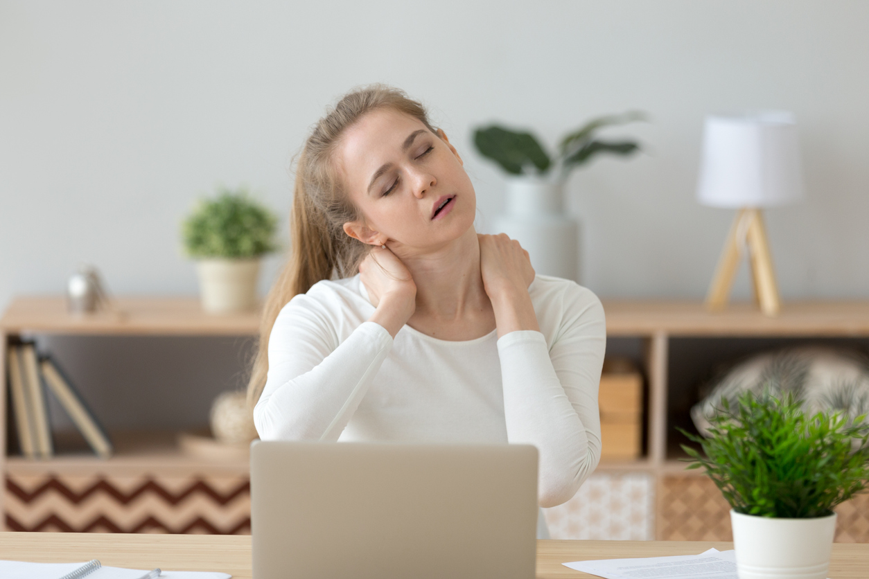 Tired fatigued young woman massaging stiff neck rubbing tensed muscles